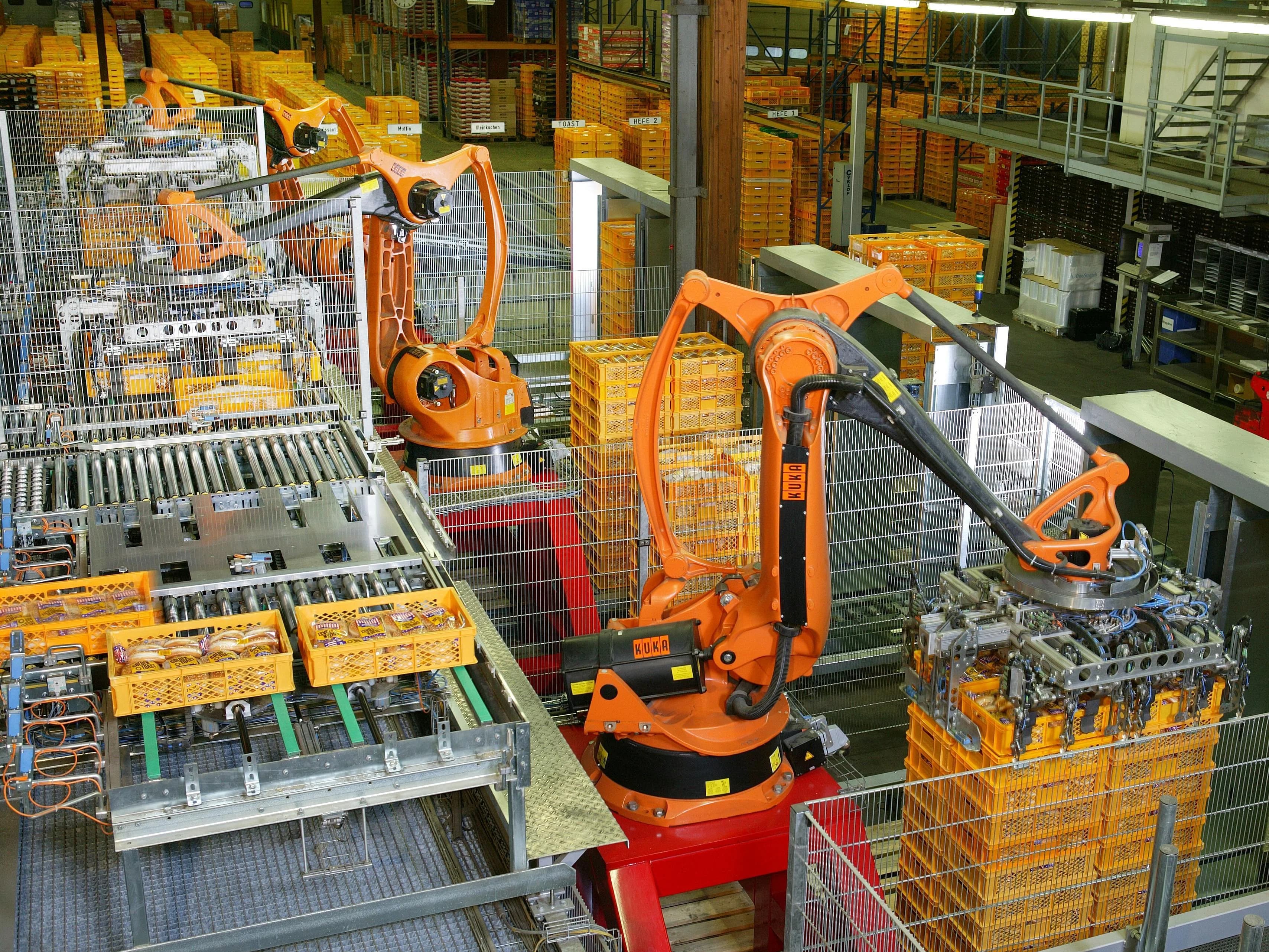 Industrial robot arms palletising goods in a factory, illustrating real process automation.