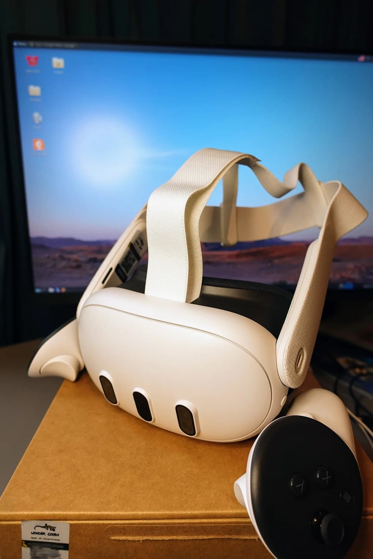A Meta Quest 3 beside a computer display and controller.